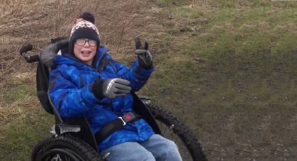 Picture of a young boy in his new wheelchair.